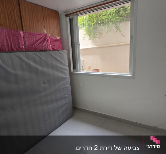 חדר ריק עם חלון פתוח ומזרן שעון על הקיר